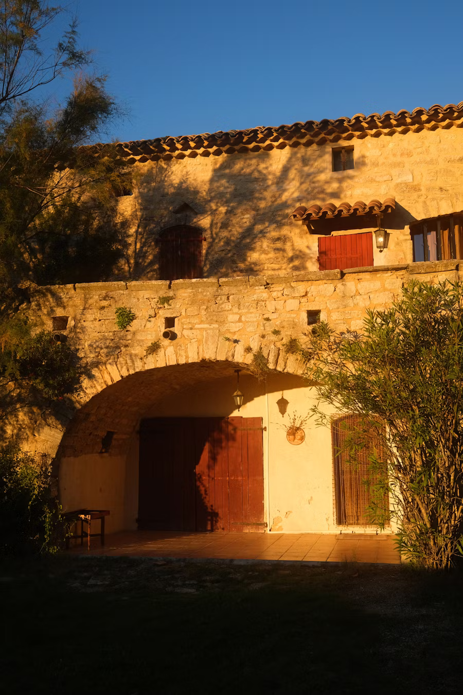 Mas en pierre au crépuscule, terrasse et porche voûté
